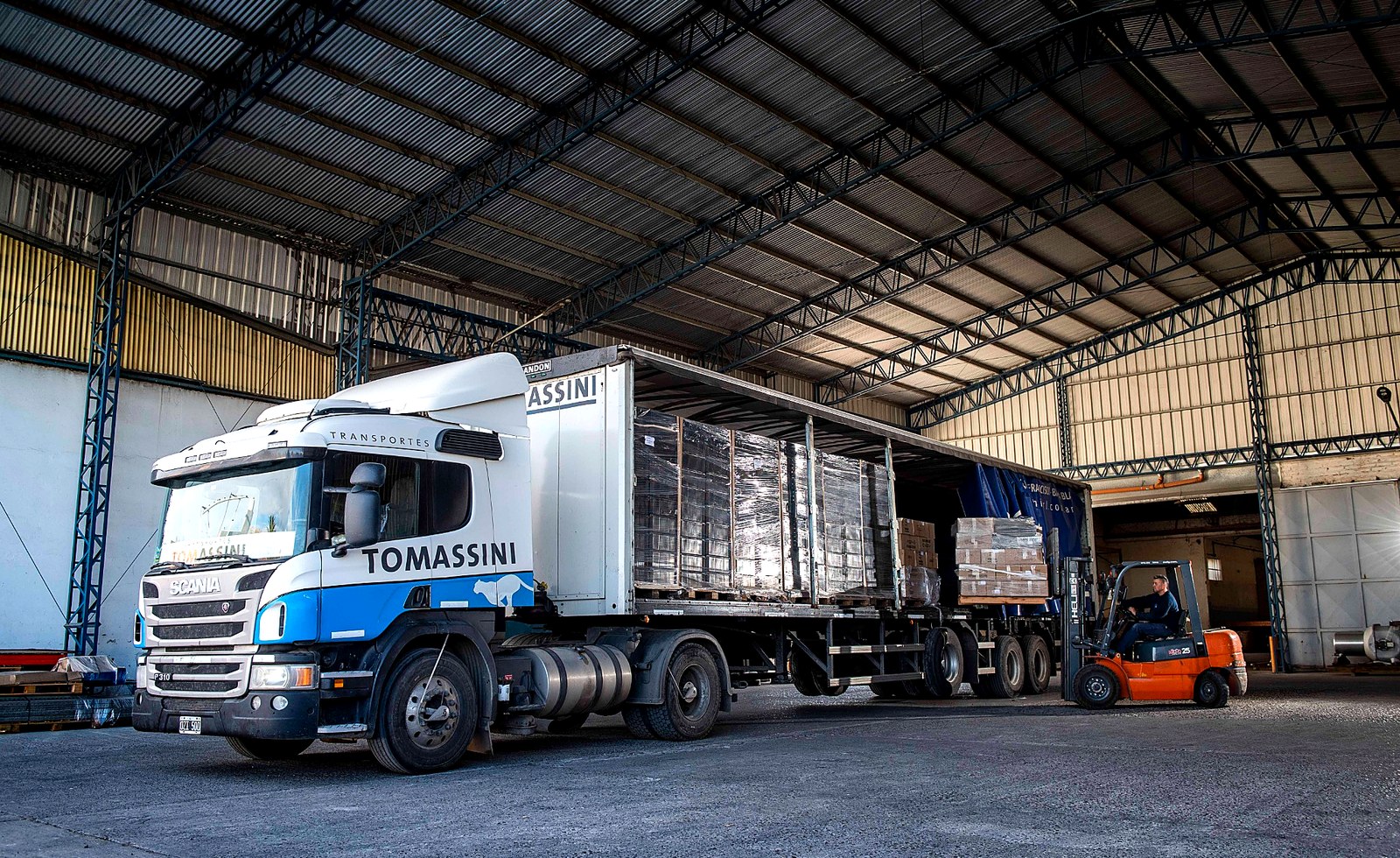Camión y autoelevador en operación de carga.