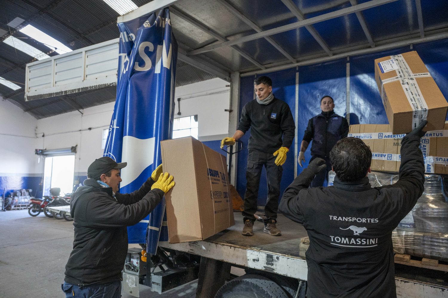 Personal de Transportes Tomassini cargando mercadería en la unidad.